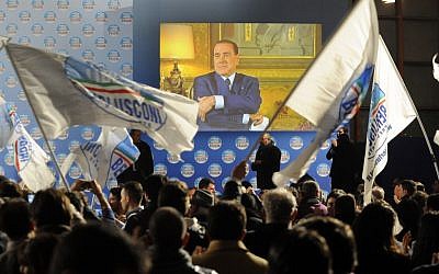 Supporters wave flags in front of a giant monitor broadcasting a message by Silvio Berlusconi during a center-right coalition rally in Naples, Italy, Friday, Feb. 22, 2013 (photo credit: AP/Salvatore Laporta)