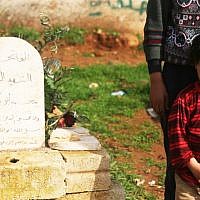 A young boy beside the grave of his relative, a fallen FSA soldier, in Qalaat al-Madik (photo: Eliyahu Kamisher)