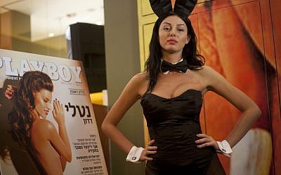 A model dressed as a Playboy bunny poses next to a poster of the first Hebrew edition of the adult magazine (photo credit: Ariel Schalit/AP)