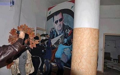 Citizen journalism image provided by Coordination Committee in Kafr Susa which has been authenticated based on its contents and other AP reporting, shows people tearing down a huge poster of President Bashar Assad and hitting it with their shoes, in Raqqa, Syria, Monday, March. 4, 2013. The activists said the picture was taken inside the Air Force Intelligence headquarters in Raqqa. (photo credit: AP/Coordination Committee In Kafr Susa)