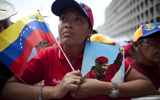 A woman holds a picture of Venezuela's President Hugo Chavez and the country's national flag in Caracas, Venezuela last Wednesday. (photo credit: AP/Ariana Cubillos)