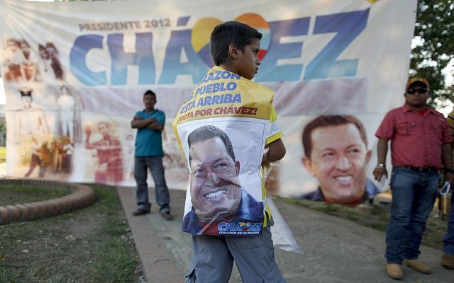 A boy stands in front of a banner of late President Hugo Chavez at the main square of his hometown, Sabaneta, in western Venezuela, Friday. (photo credit: AP/Esteban Felix)
