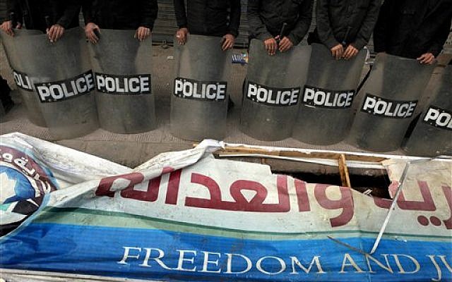Egyptian anti-riot soldiers stand guard in front of a destroyed banner of the Muslim Brotherhood's Freedom and Justice Party in Cairo, Egypt, Friday, March 22, 2013. (photo credit: AP/Amr Nabil)