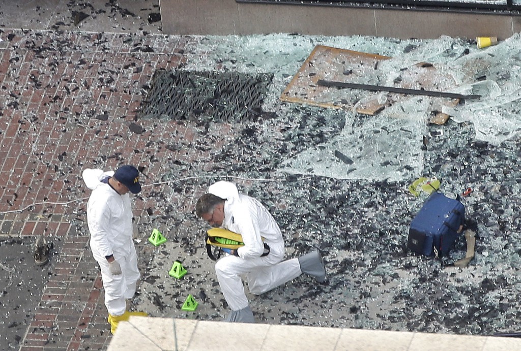 Two men in hazardous materials suits put numbers on the shattered glass and debris as they investigate the scene at the first bombing on Boylston Street in Boston Tuesday, April 16, 2013 near the finish line of the 2013 Boston Marathon, a day after two blasts killed three and injured over 170 people (photo credit: Elise Amendola/AP)