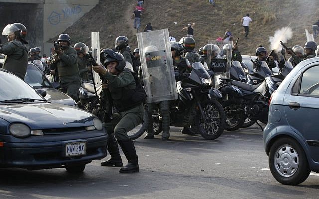 Riot police fire rubber bullets as demonstrators throw rocks against them during clashes after opposition supporters and students blocked a highway in the Altamira neighborhood in Caracas, Venezuela, on Monday, April 15, 2013(AP Photo/Fernando Llano)