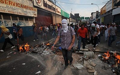 Opposition supporters and students cross a barricade during clashes with riot police in Caracas, Venezuela, on Monday, April 15, 2013. (photo credit: AP Photo/Fernando Llano)