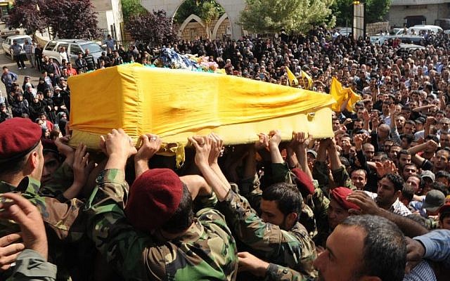Hezbollah fighters in military uniform carry the coffin of one of their own, Hassan Faisal Shuker, 18, who was killed in a battle against Syrian rebels in the town of Qusair, Syria, in May, 2013 (photo credit: AP)