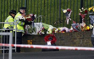 Police officers lay down floral tributes handed to them by members of the public Thursday at the scene of the terror attack in Woolwich, southeast London, a day earlier. (photo credit: AP/Sang Tan)