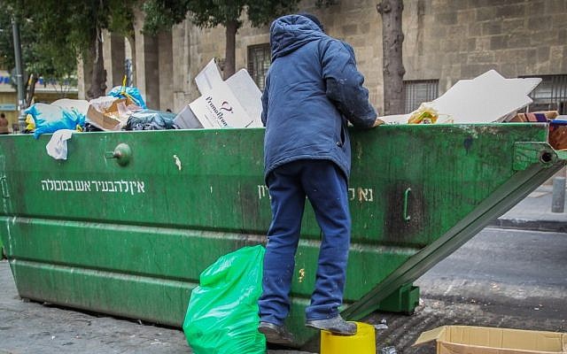A man searches the trash in a garbage container in the center of Jerusalem. (illustrative photo by Nati Shohat/Flash90)