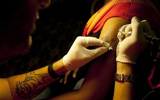 Wassim Razzouk tattoos an Ethiopian Christian Orthodox pilgrim in a hotel in Jerusalem, Monday, May 13, 2013. (photo credit: AP/Dusan Vranic)