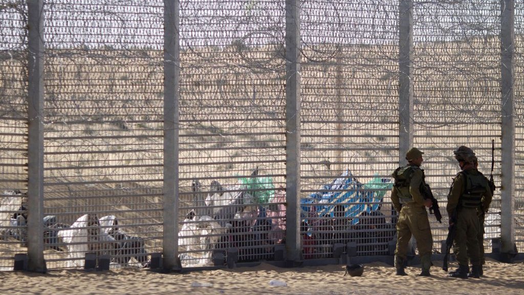 African refugees sit behind a border fence after they attempted to cross illegally from Egypt into Israel as Israeli soldiers stand guard near the border with Egypt, in southern Israel, on September 4, 2012. (photo credit: AP/Ariel Schalit, File)