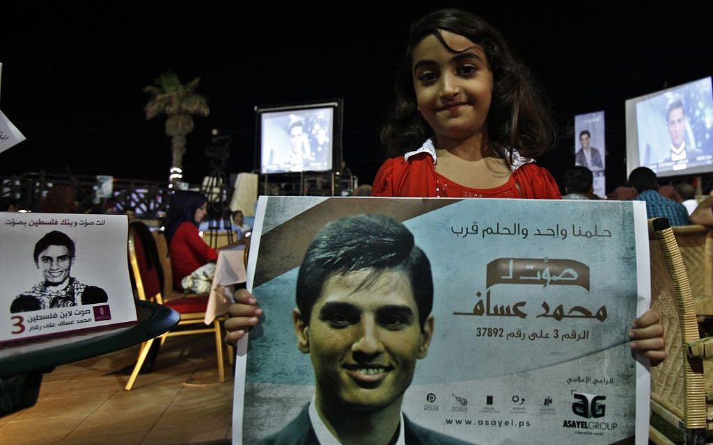 A Palestinian girl carries a poster of singer Mohammed Assaf, 23, while watching the televised performance of the Palestinian finalist on the Arab Idol talent show, in Gaza City, Friday, June 21 (photo credit: AP/Adel Hana)