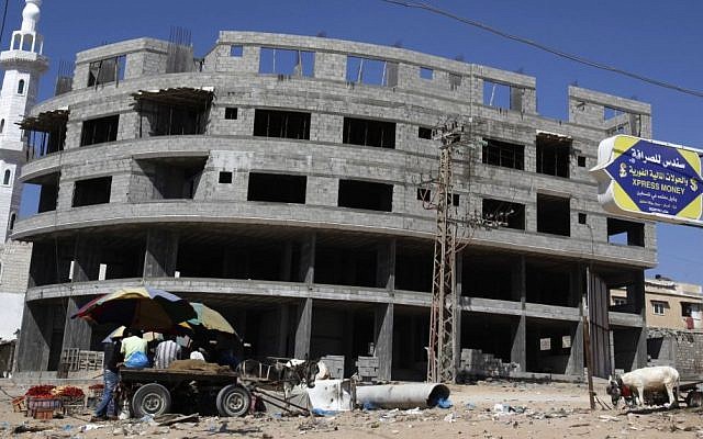 Palestinian vendors sit in front of a building under construction at the main road in Gaza City, Thursday, June 27, 2013 (photo credit: AP/Adel Hana)