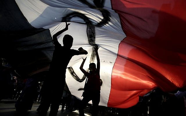 Opponents of Egypt's Islamist President Mohammed Morsi hold a large Egyptian national flag during a protest outside the presidential palace, in Cairo, Egypt, Tuesday, July 2, 2013 (photo credit: AP/Hassan Ammar)