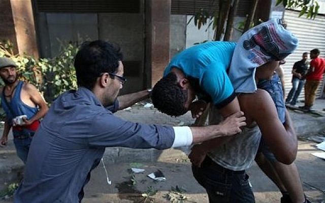 Opponents of ousted President Mohammed Morsi carry their injured friend who was wounded during clashes with Morsi supporters, in Cairo, Egypt, Monday, July 22, 2013. (photo credit: AP Photo/Hussein Malla)