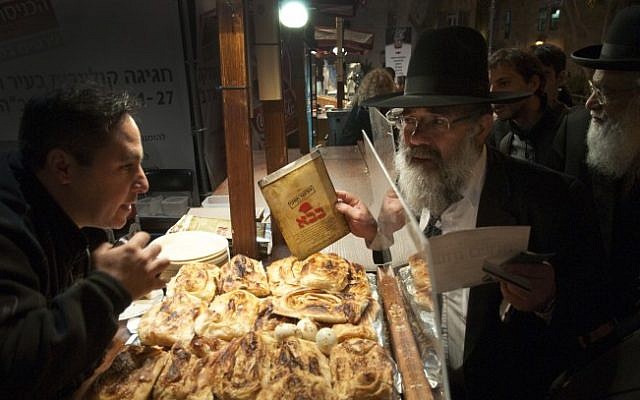 Illustrative photo of a representative of Israel's Chief Rabbinate inspecting a kosher certificate at a food stand in Jerusalem. (Rubin Salvadori/Flash90/File)