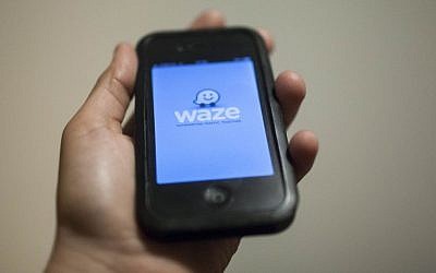 A man holds an iPhone displaying the Waze app (photo credit: Yonatan Sindel/Flash90)