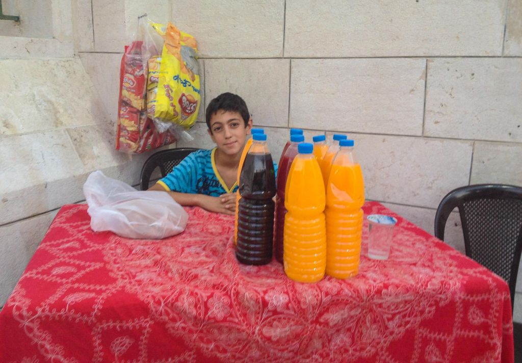 A young Ammani sets up a juice stand outside a mosque for people to break their fast with (photo credit: Michal Shmulovich/Times of Israel)