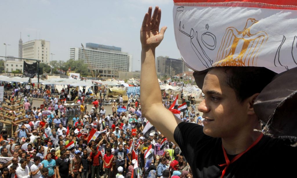 An Egyptian protester covers his head by a national flag during a demonstration against Egypt's Islamist President Mohammed Morsi in Tahrir Square in Cairo, Monday, July 1, 2013 (AP Photo/Amr Nabil)