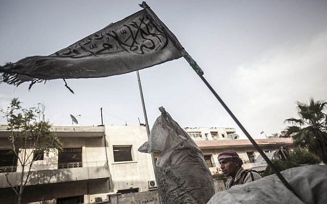 A rebel fighter stands guard at a checkpoint flying an Islamic banner near the front line in Aleppo, Syria. (photo credit: AP/Narciso Contreras)