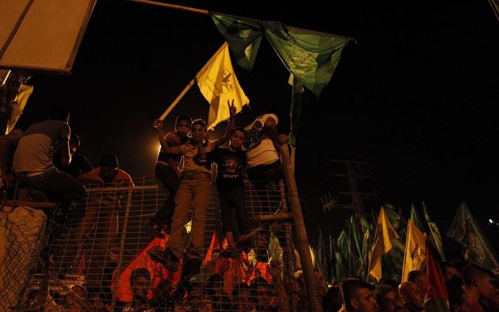 Palestinians celebrate and wave green Hamas and yellow Fatah flags as they wait for the released prisoners at a checkpoint at the entrance of Beit Hanoun between the northern Gaza Strip and Israel on Tuesday, Aug. 13, 2013. (photo credit: AP photo/Hatem Moussa)