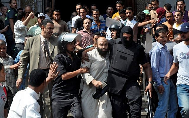 Egyptians security forces escort an Islamist supporter of the Muslim Brotherhood out of the al-Fatah mosque, after hundreds of Islamist protesters barricaded themselves inside the mosque overnight, following a day of fierce street battles that left scores of people dead, near Ramses Square in downtown Cairo, Egypt, Saturday, August 17, 2013 (photo credit: AP/Hussein Tallal)