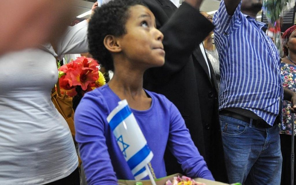 A young Ethiopian-Israeli girl looks up at the screen to see some 450 Falash Mura descending from two planes at Ben Gurion Airport in August, 2013 (photo credit: Michal Shmulovich/ToI)