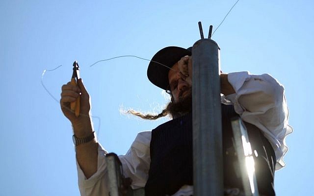 Illustrative photo of an ultra-Orthodox man hanging an eruv wire in the Gilo neighborhood of Jerusalem, Israel. (photo credit: Nati Shohat/Flash90/File)