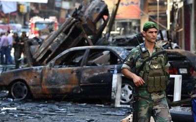 A Lebanese army soldier passes in front of burned cars at the site of a car bomb explosion, in an overwhelmingly Shiite area and stronghold of the Lebanese militant group Hezbollah, at the southern suburb of Beirut, Lebanon, August 16, 2013 (photo credit: AP Photo/Hussein Malla, File)