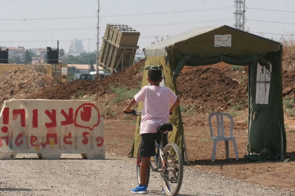 A boy next to a stop sign in front of an Iron Dome anti-missile battery near Tel Aviv. (photo credit: Roni Schutzer/Flash90)