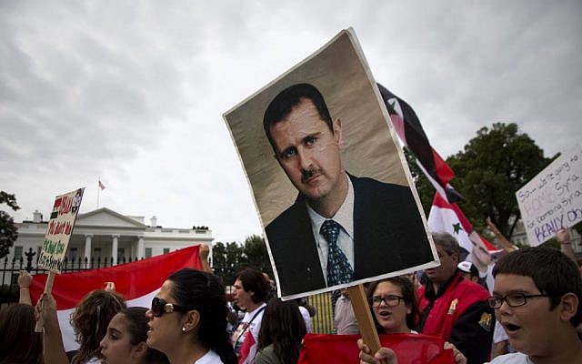 Protesters carry an image of Syrian President Bashar Hafez al-Assad during a demonstration against US military action in Syria, Monday, Sept. 9, 2013, in front of the White House in Washington (photo credit: AP/Carolyn Kaster)