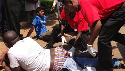 An injured man is treated outside an upscale shopping mall in Nairobi, Kenya, after an attack there left at least 15 people dead, Saturday Sept 21, 2013 (AP Photo/ Jason Straziuso)