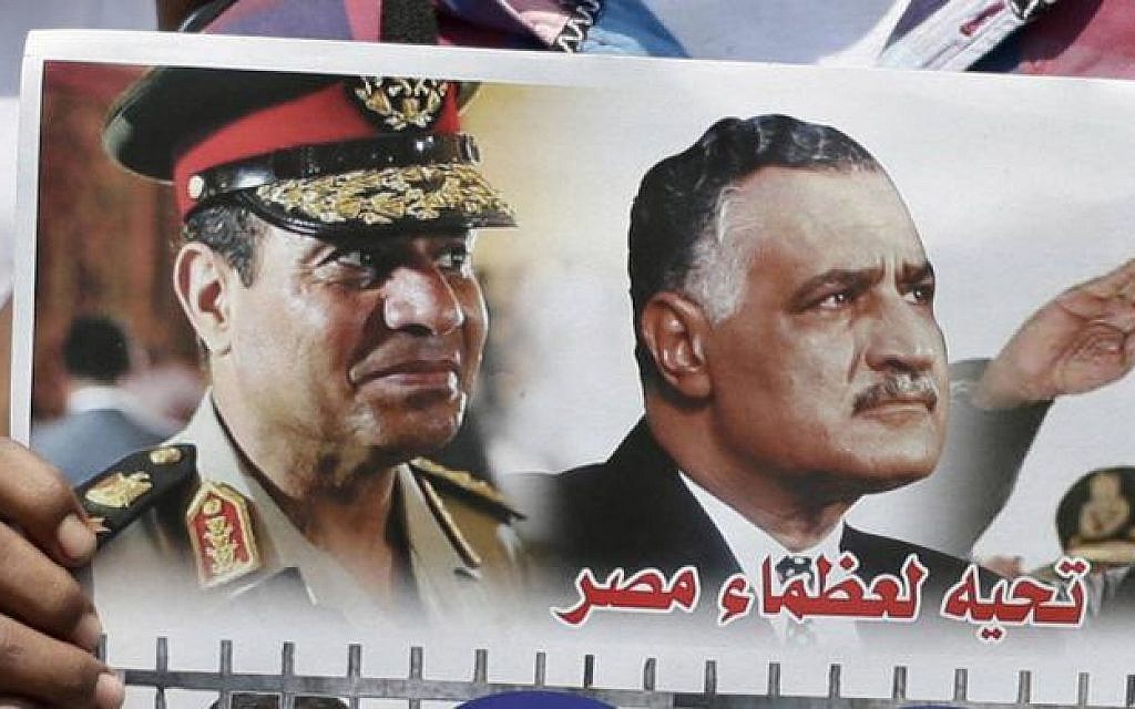 In this July 12, 2013, photo, Egyptian policemen hold a picture with portraits of Army Chief Gen. Abdel Fattah el-Sissi and former Egyptian president Gamal Abdel Nasser at Tahrir Square, in Cairo. Arabic in the picture reads,'Salutation to the great men of Egypt,' (photo credit: AP)