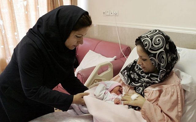 Iranian nurse Zahra Akbarzadeh, left, gives one-day-old baby girl Setayesh to her mother, Tayyebeh Sadat Bidaki, to feed her at the Mehr hospital, in Tehran, Sunday, July 29, 2012 (photo credit: AP/Vahid Salemi)