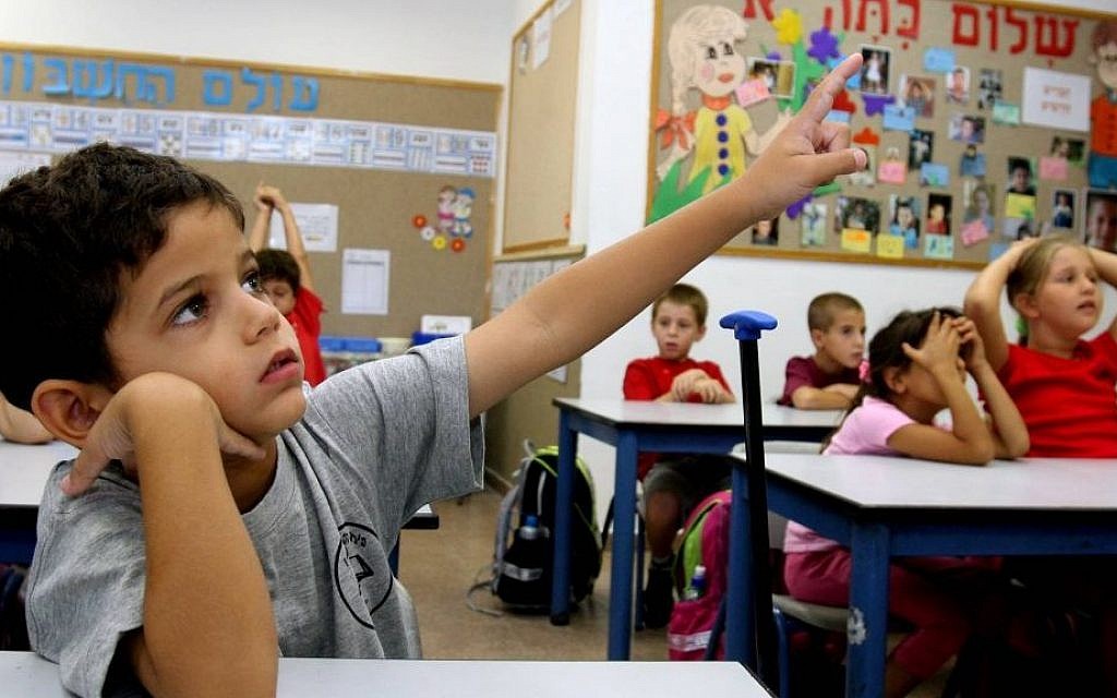 A first grader raises his hand in a classroom in Nitzan, southern Israel. (Edi Israel/Flash90/File)
