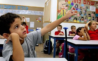 A first grader raises his hand in a classroom in Nitzan, southern Israel. (Edi Israel/Flash90/File)