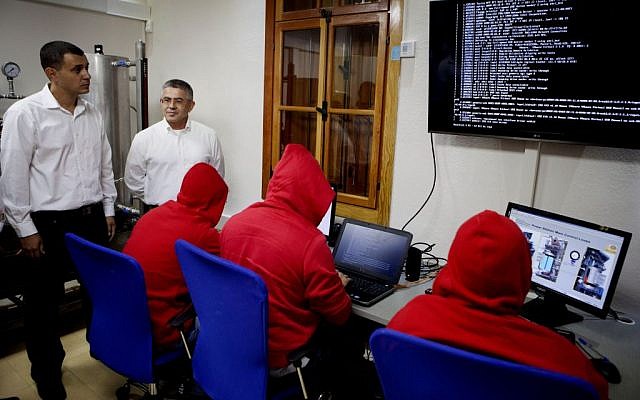 Israel Electric Corporation Vice President, Yasha Hain (second left), and Ofir Hason watch a cyber team at work at the CyberGym school in Hadera, October 20, 2013. AP/Dan Balilty)