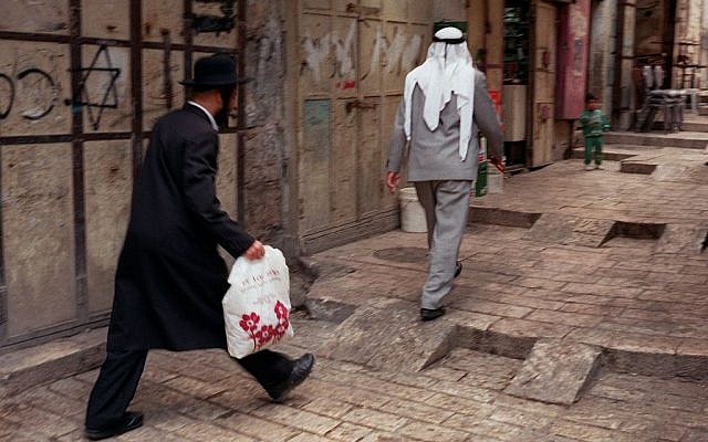 In this June 12, 1997 file photo, an Orthodox man walks behind a Palestinian man on a street in the walled Old City of Jerusalem. (photo credit: AP/Greg Marinovich, File)