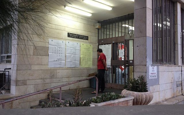 A man reading bulletins outside a Jerusalem voting station just before polls opened Tuesday morning. (photo credit: Joshua Davidovich / Times of Israel staff)