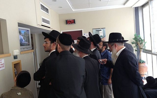 Followers of Rabbi Ovadia Yosef watch the television news to learn of his condition while waiting at the hospital where he was being treated shortly before he died, October 7, 2013. (photo credit: Mitch Ginsburg)