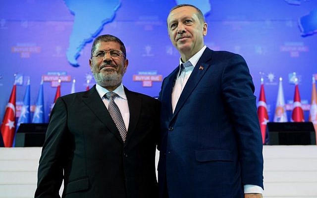 In this Sunday, Sept. 30, 2012 file photo provided by Turkish Prime Minister's Press Service, Turkey's Prime Minister Recep Tayyip Erdogan, right, and then-Egyptian president Mohammed Morsi salute the members of Turkey's ruling Justice and Development Party in Ankara, Turkey (photo credit: AP/Kayhan Ozer)