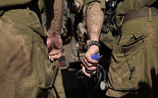 An Israeli army paramedic stands with a bloodied hand after treating a civilian shot near the Israel-Gaza border, Tuesday, Dec. 24, 2013. (photo credit: AP/Tsafrir Abayov)
