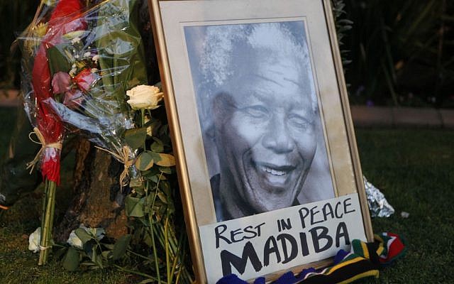 A framed portrait of former president Nelson Mandela and flowers are placed outside Mandela's Johannesburg home Friday, December 6, 2013. (photo credit: AP/Denis Farrell)