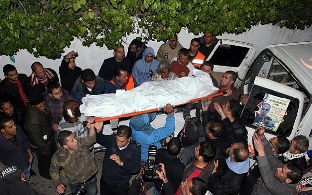 Palestinian men stand next to the body of Mustafa Tamimi on its way to a hospital morgue in the West Bank city of Ramallah, on December 10, 2011. (photo credit: Issam Al Rimawi/Flash90)