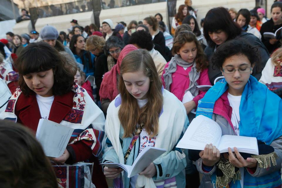 Eliza Moss-Horwitz, Lucy Sattler and Alexandra Schwartz pray with Women of the Wall. Schwartz (right) holds an empty Torah cover beneath her prayer book, symbolizing the Torah scroll the group was prevented from bringing in to the Kotel plaza, January 2014. (photo credit: Courtesy of Moving Traditions)