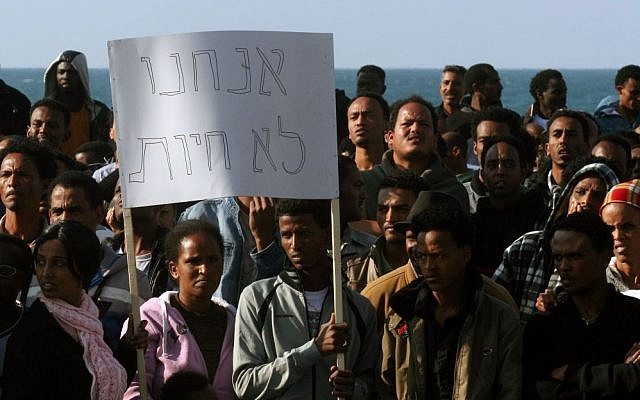 African asylum seekers hold up a sign that reads, 'We are not animals' during a protest outside the US Embassy in Tel Aviv, on Monday (photo credit: Roni Schutzer/Flash90)