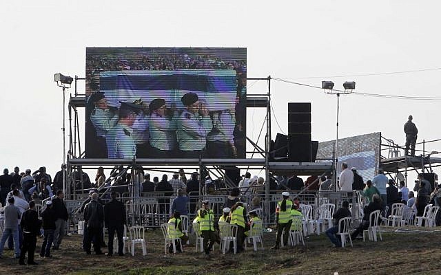 Spectators at the Sycamore Ranch watch a screen depicting IDF major generals bearing the coffin of former prime minister Ariel Sharon, Sunday, January 13, 2014 (photo credit: Miriam Alster/Flash90)