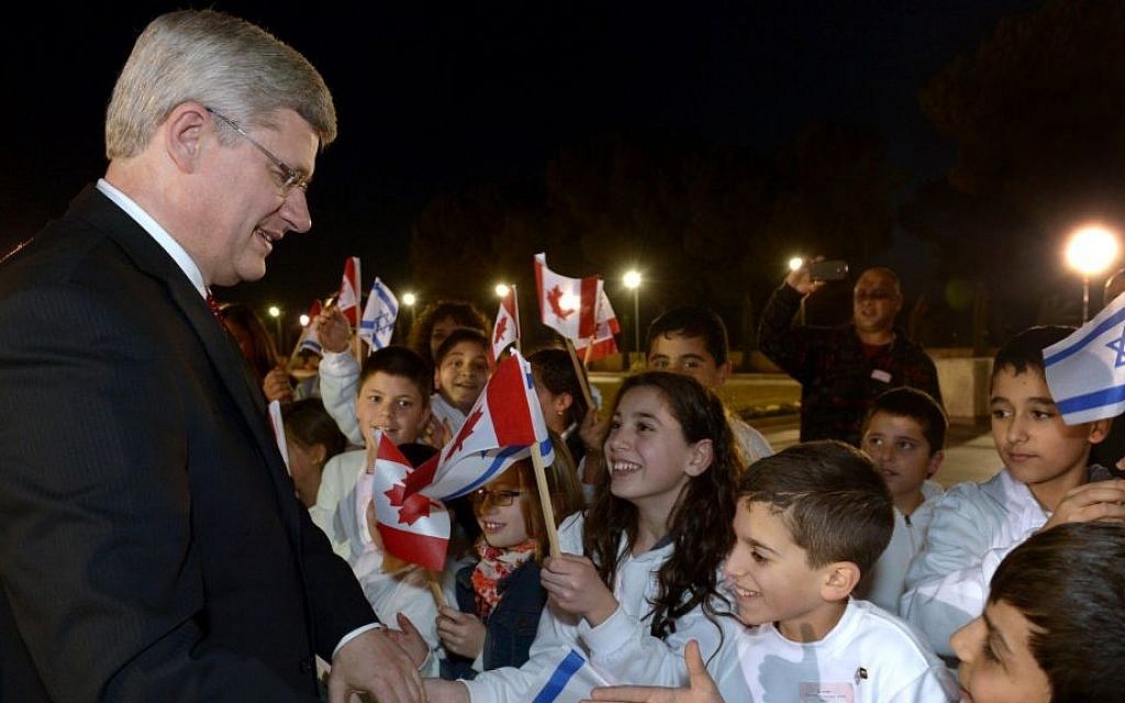 Canadian Prime Minister Stephen Harper is greeted by children waving Canadian and Israeli flags, during his official state visit to Israel, on Monday, January 20, 2014. (Haim Zach/GPO/Flash 90)