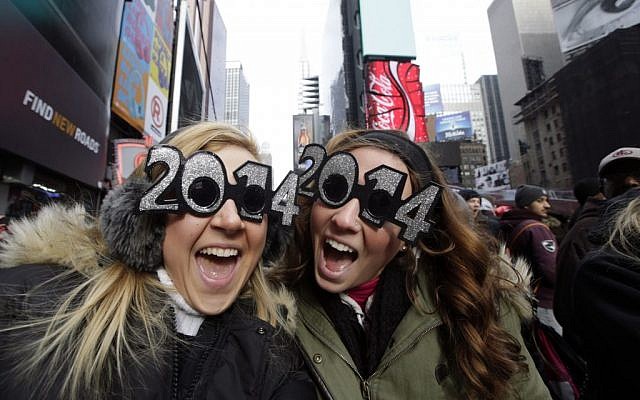 Two revelers ready to party pose for a photo with their 2014 glasses while waiting for the celebration to begin in Times Square on New Year's Eve, Tuesday, Dec. 31, 2013, in New York. (photo credit: AP/Kathy Willens)