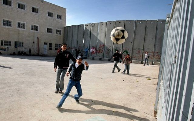 Illustrative: Palestinian schoolchildren playing soccer around the security barrier in the West Bank (Flash 90)